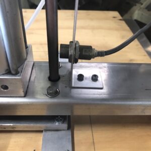 Close-up of a metal apparatus with bolts and a lever on a wooden table.