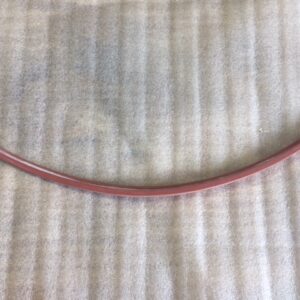 A red hula hoop resting against a vertically striped curtain.