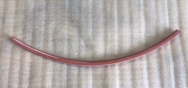 A red hula hoop resting against a vertically striped curtain.