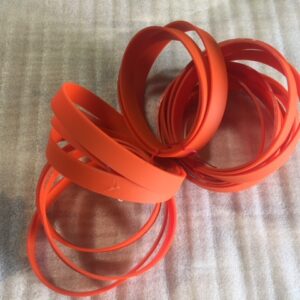 Two orange spiral hair accessories on a light background.