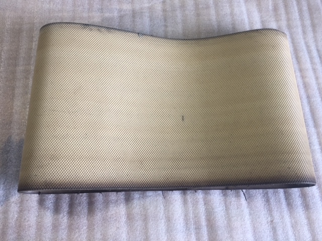 Curved, textured beige surface with faint markings on a striped fabric background.