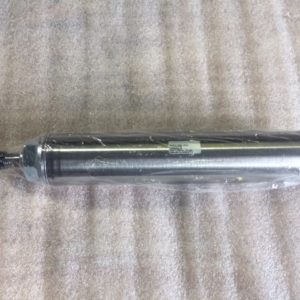 A metallic cylindrical object with a small opening, lying on a textured surface.