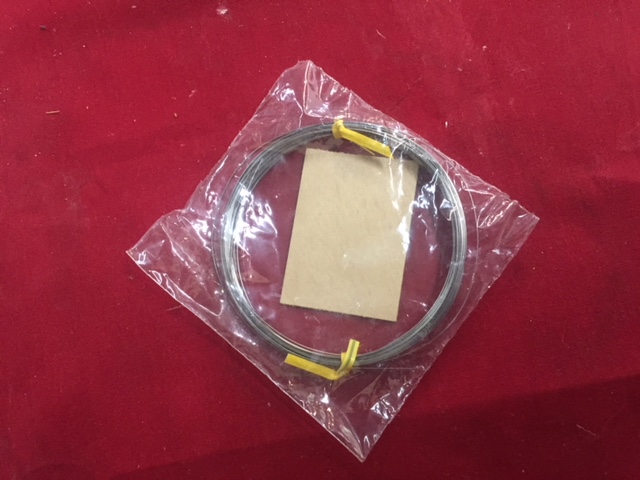 A coiled cable with yellow connectors in a plastic bag on a red surface.