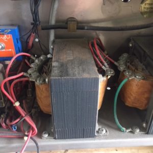 Interior view of an electrical transformer with coils and wiring.