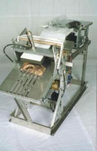 Small industrial machine with conveyor belt and rollers.