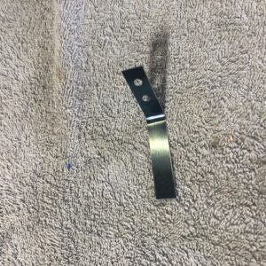 Small metal bracket with holes on a textured surface.