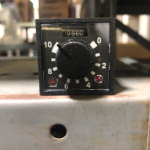 Close-up of a black timer dial set to 0 seconds on a metal surface.