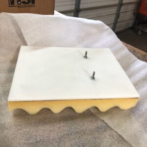 White foam panel with yellow base and two screws on top.