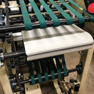 Close-up of a conveyor belt system with green rollers and a white belt.