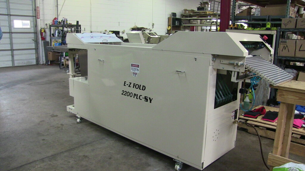 Industrial folding machine in a workshop setting.