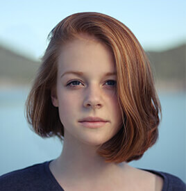 Portrait of a young woman with red hair against a natural background.